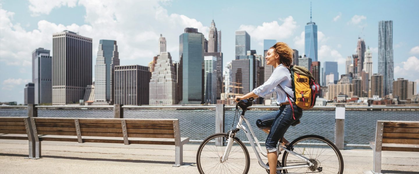 African American woman riding a bike in NYC on a beautiful summer day - transporastion concepts