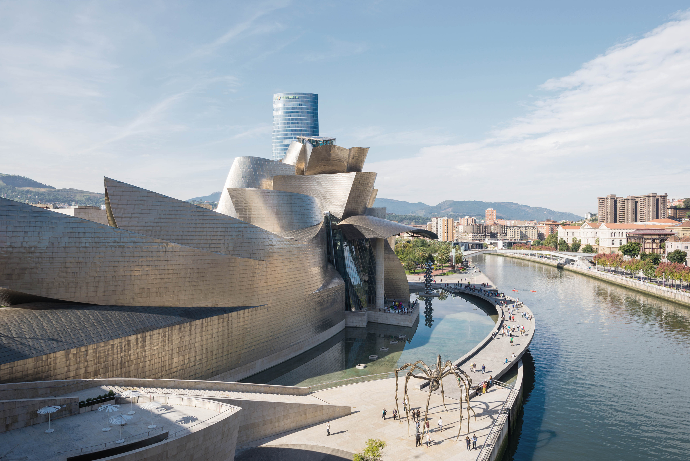 Bilbao, Spain - October 06, 2016. People strolls along the riverside promenade at the Nervión river that runs through the city into the Cantabrian Sea. On the left side, the world famous Guggenheim Museum. It is the main attraction in Bilbao