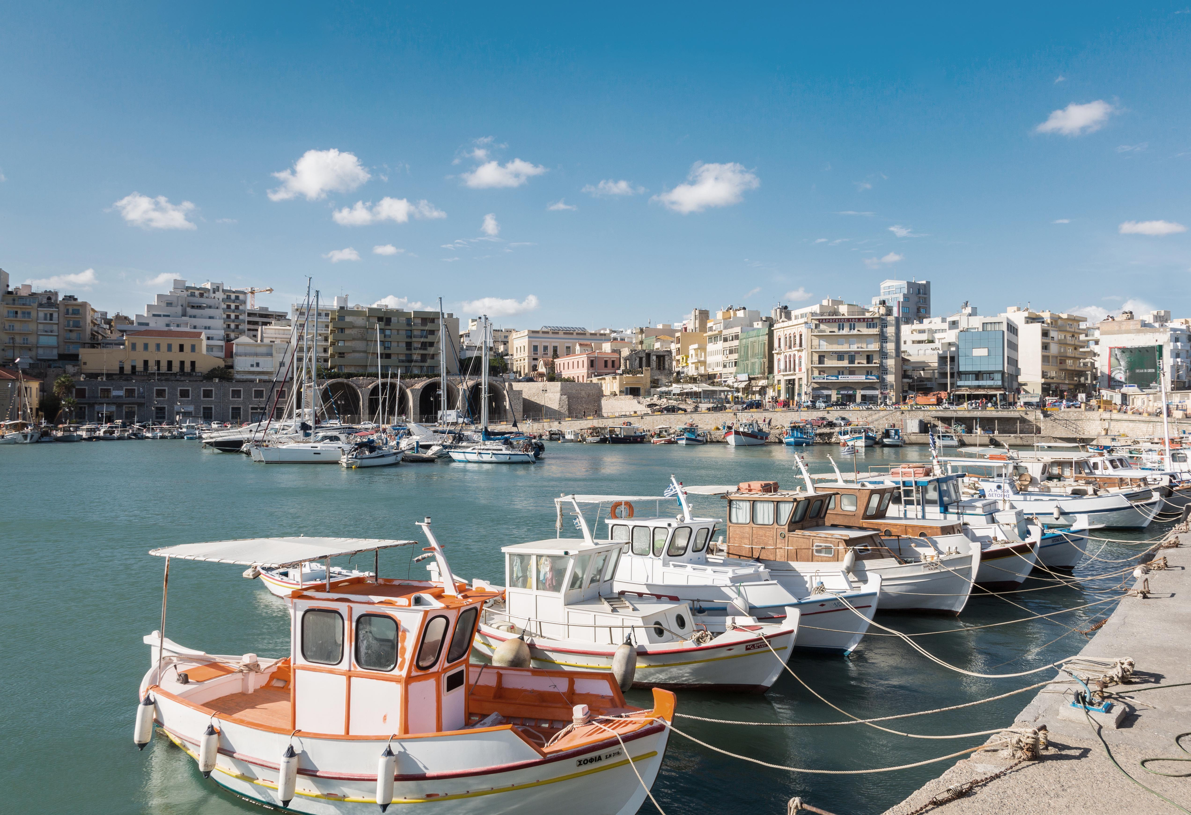 Heraklion, Greece - September 23, 2013. Dozens of little fishing boats are tied up in a row in front of the Venetian Arsenal in the Old Port of Heraklion.