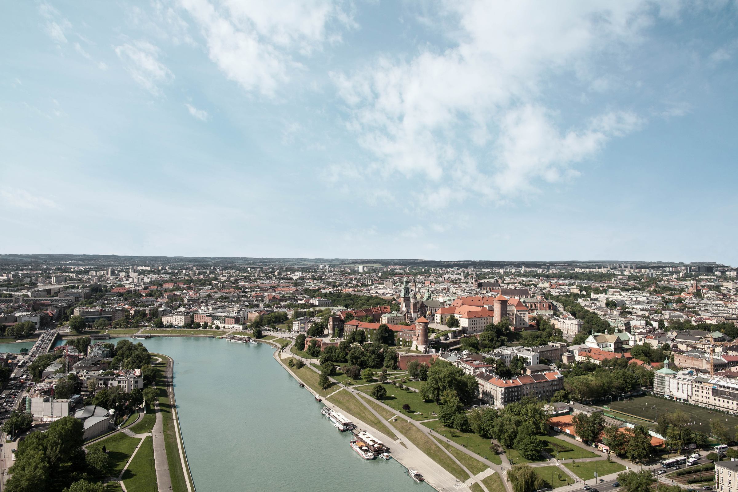 View from above of the Wawel Royal Castle, Old Town of Krakow and Vistula river during sunny day with white clouds.