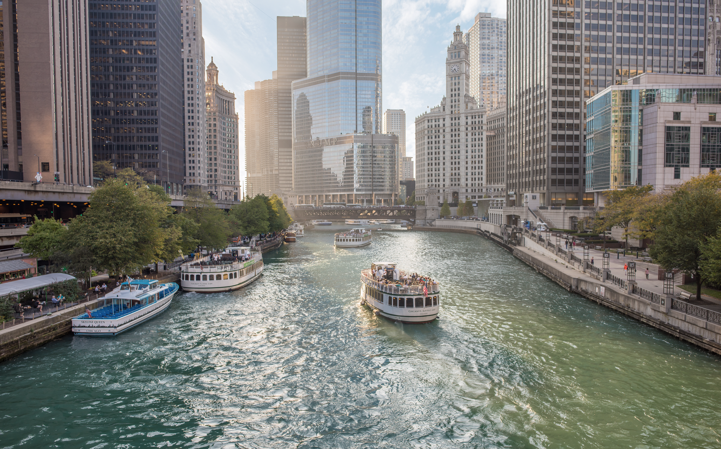 Chicago, IL, Sept. 21, 2017: A cruise boat carries passengers along the Chicago River at sunset, with skyscrapers in the distance.