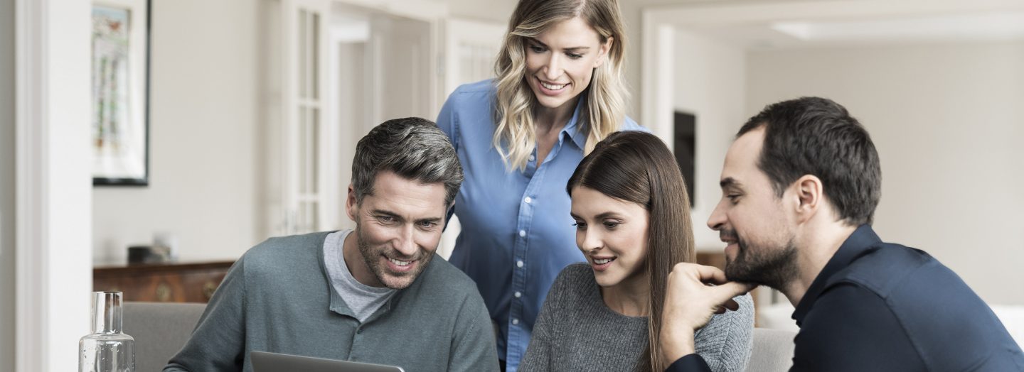 Four people search for flights on a laptop