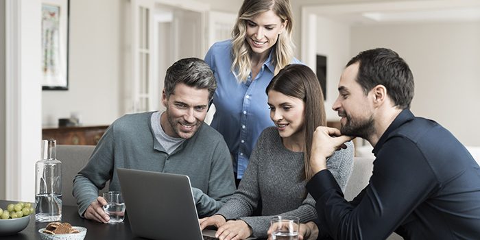 Four people search for flights on a laptop