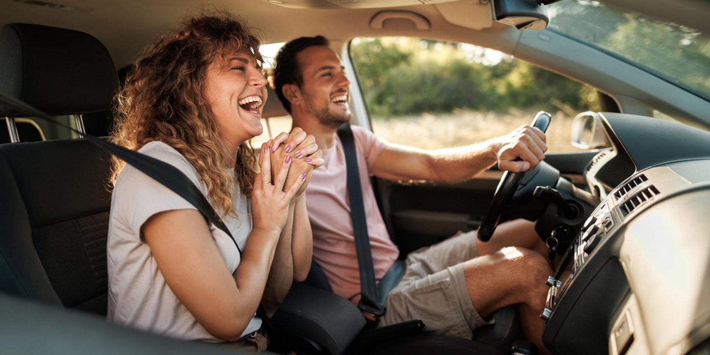 Couple sitting together in the car holding hands.