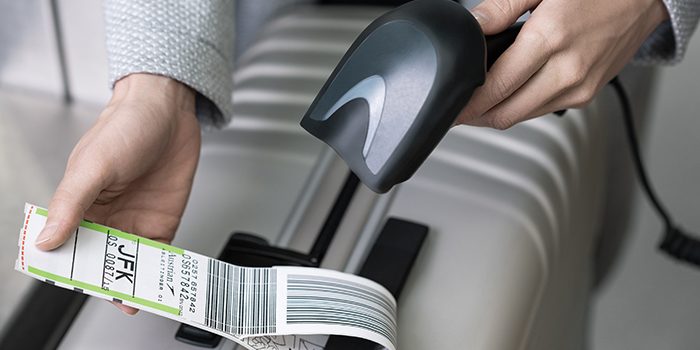 A person scans the luggage tag on their suitcase